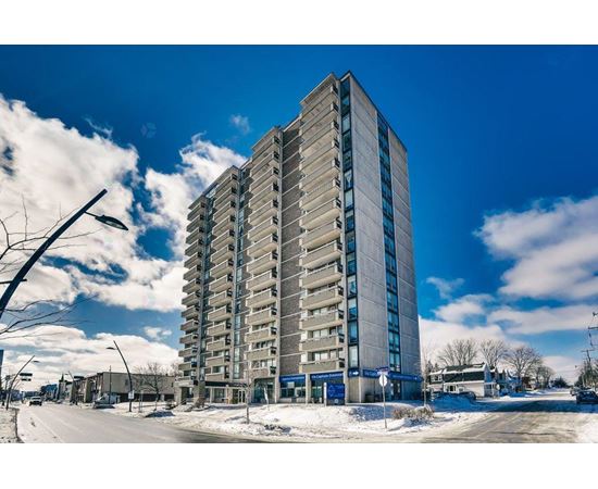 A tall residential building stands in the middle of a snowy street.