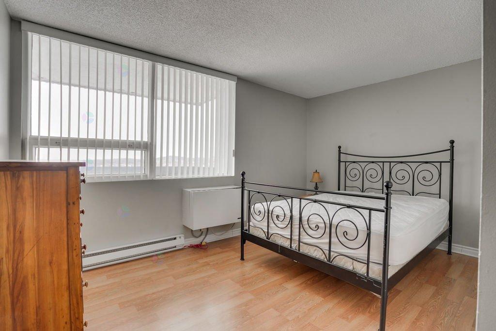 A bedroom with a metal bed frame and a wooden dresser.