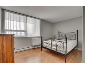 A bedroom with a metal bed frame and a wooden dresser.