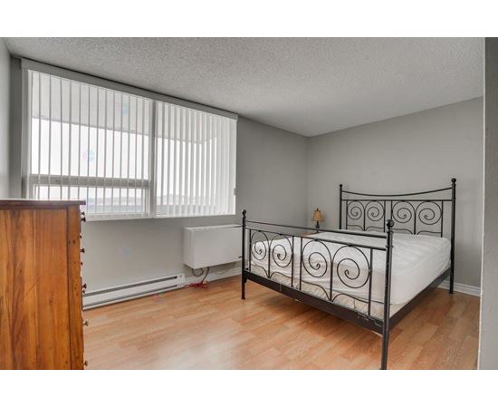 A bedroom with a metal bed frame and a wooden dresser.