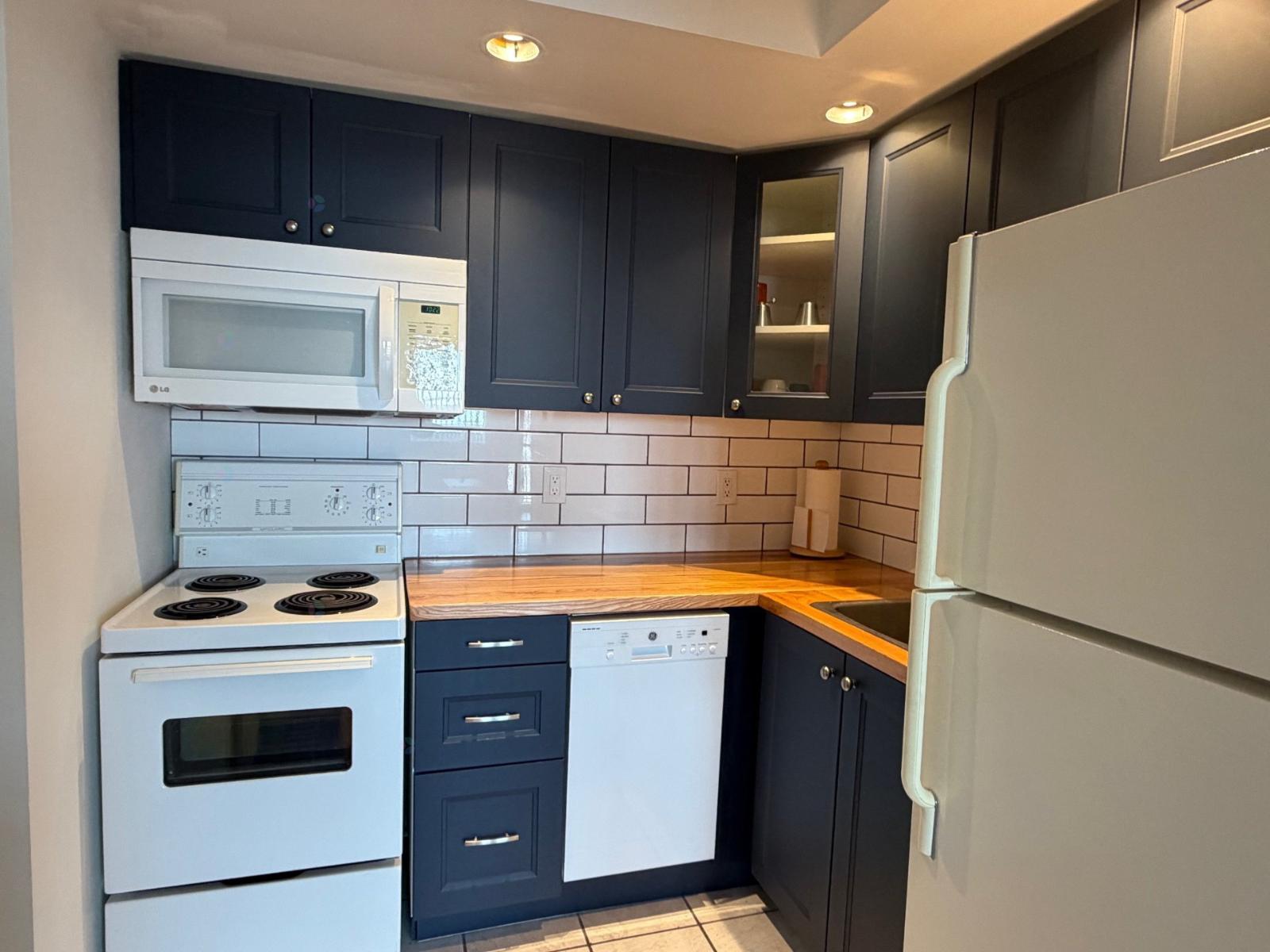 A kitchen with black cabinets and white appliances.