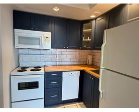 A kitchen with black cabinets and white appliances.