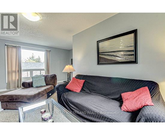 A living room with a grey couch, a coffee table, and a painting on the wall.