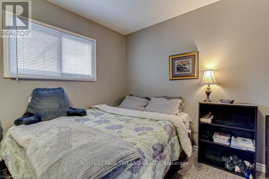 A bedroom with a bed, a nightstand with a lamp, and a bookshelf.
