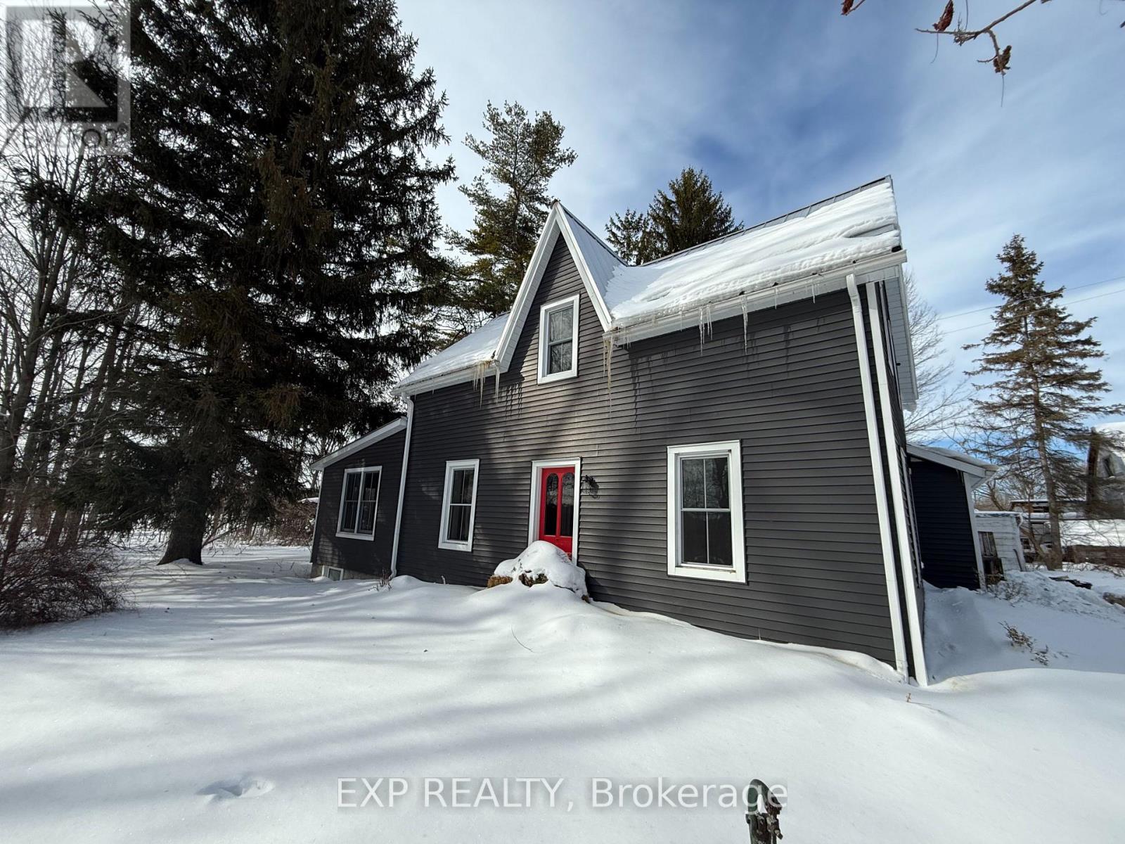 A house with a red door is surrounded by snow.