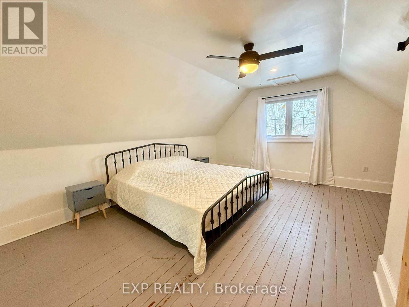 A bedroom with a bed, nightstand, and window.