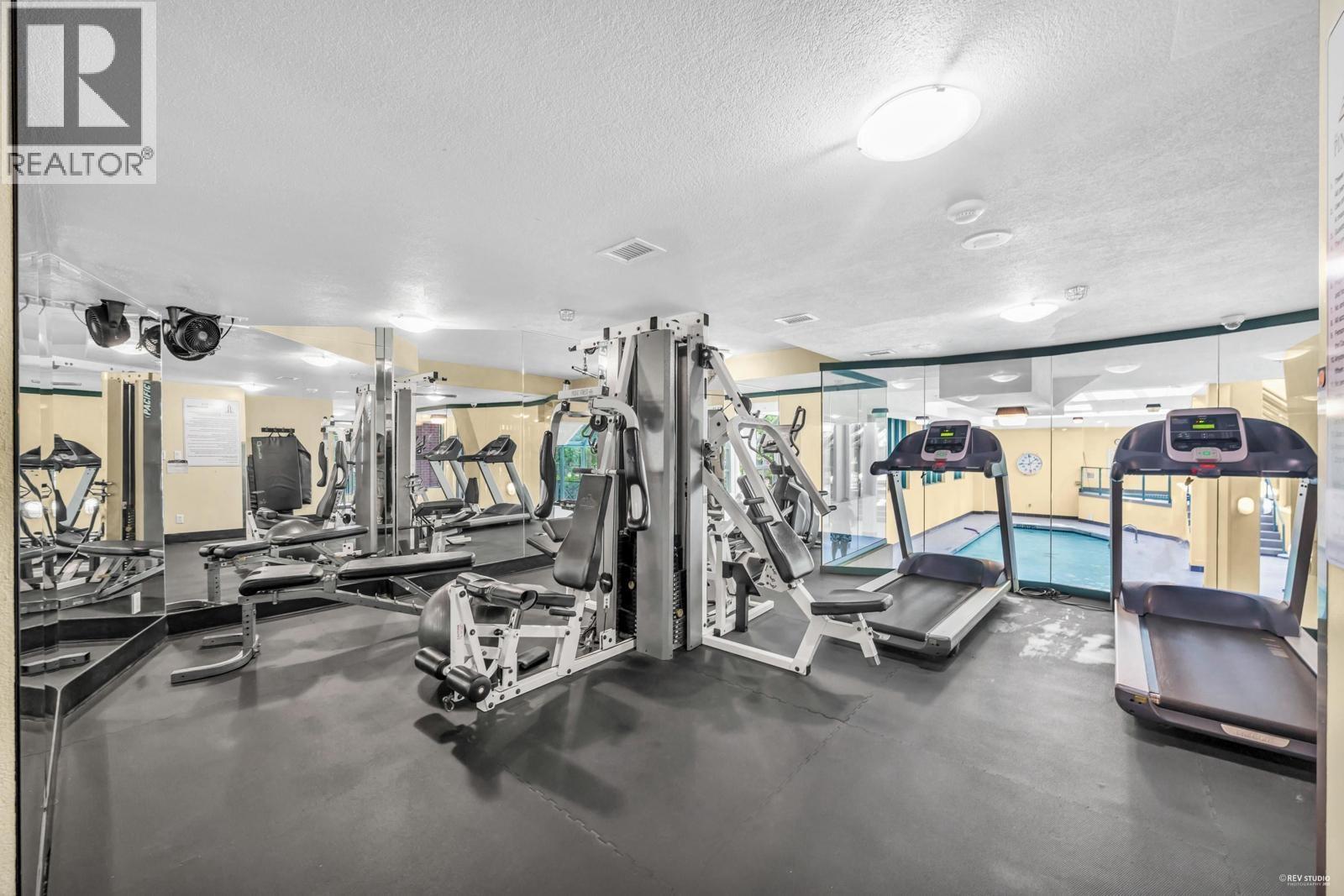 A gym with a variety of equipment including treadmills, weights, and exercise machines.