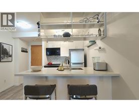 A kitchen with a white countertop and two black chairs.
