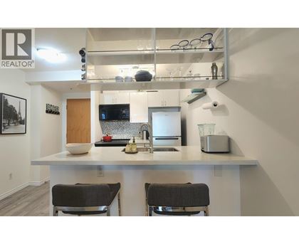 A kitchen with a white countertop and two black chairs.
