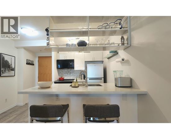 A kitchen with a white countertop and two black chairs.