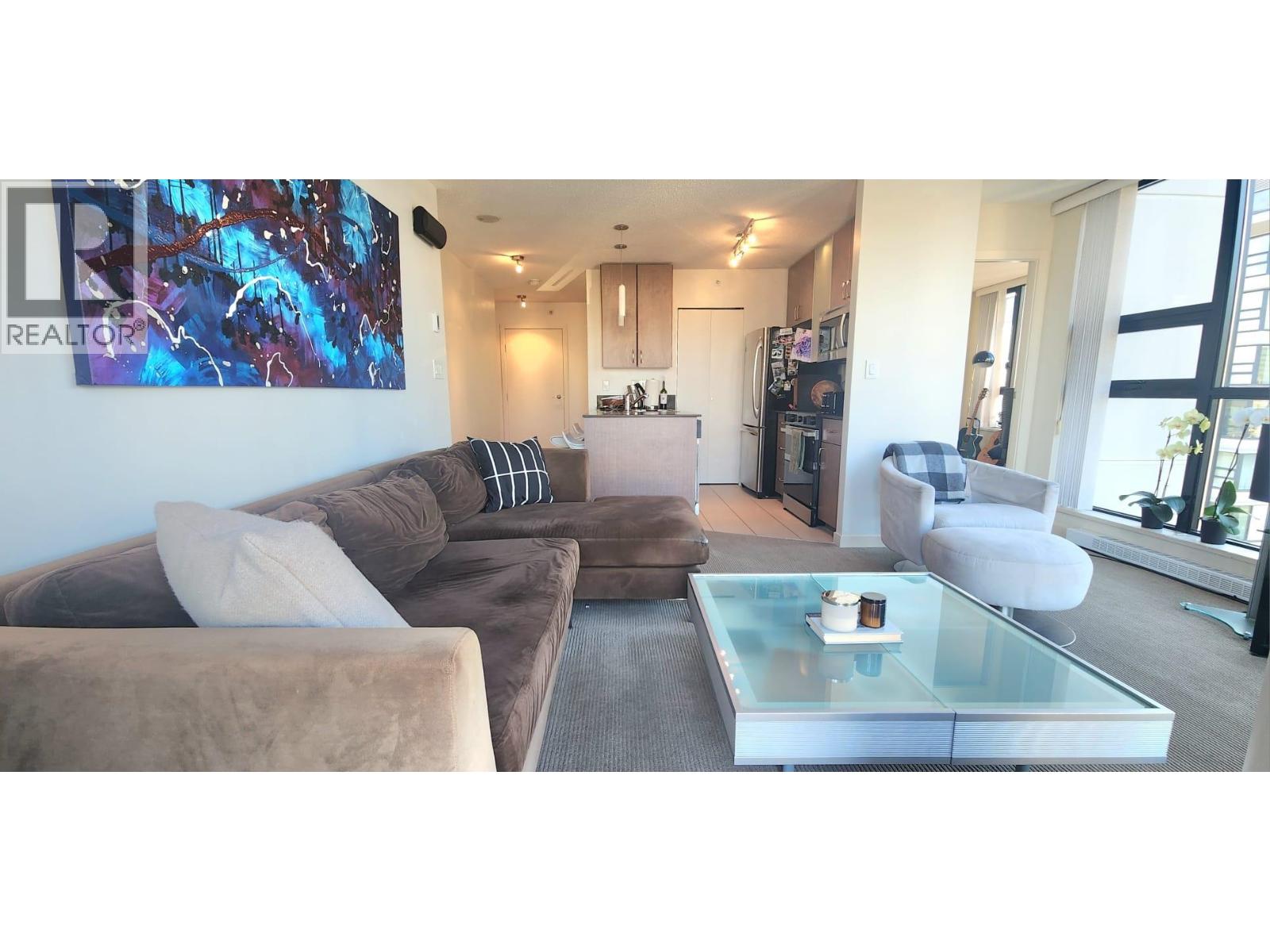 A living room with a brown couch and a glass coffee table.