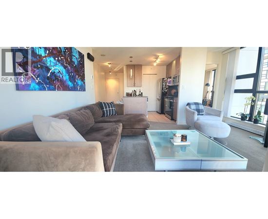 A living room with a brown couch and a glass coffee table.