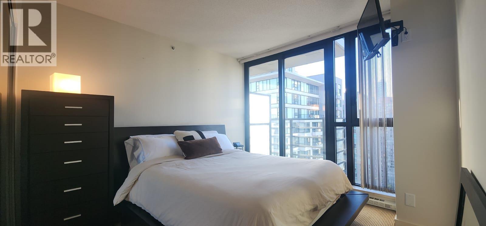 A bedroom with a large bed and a sliding glass door.