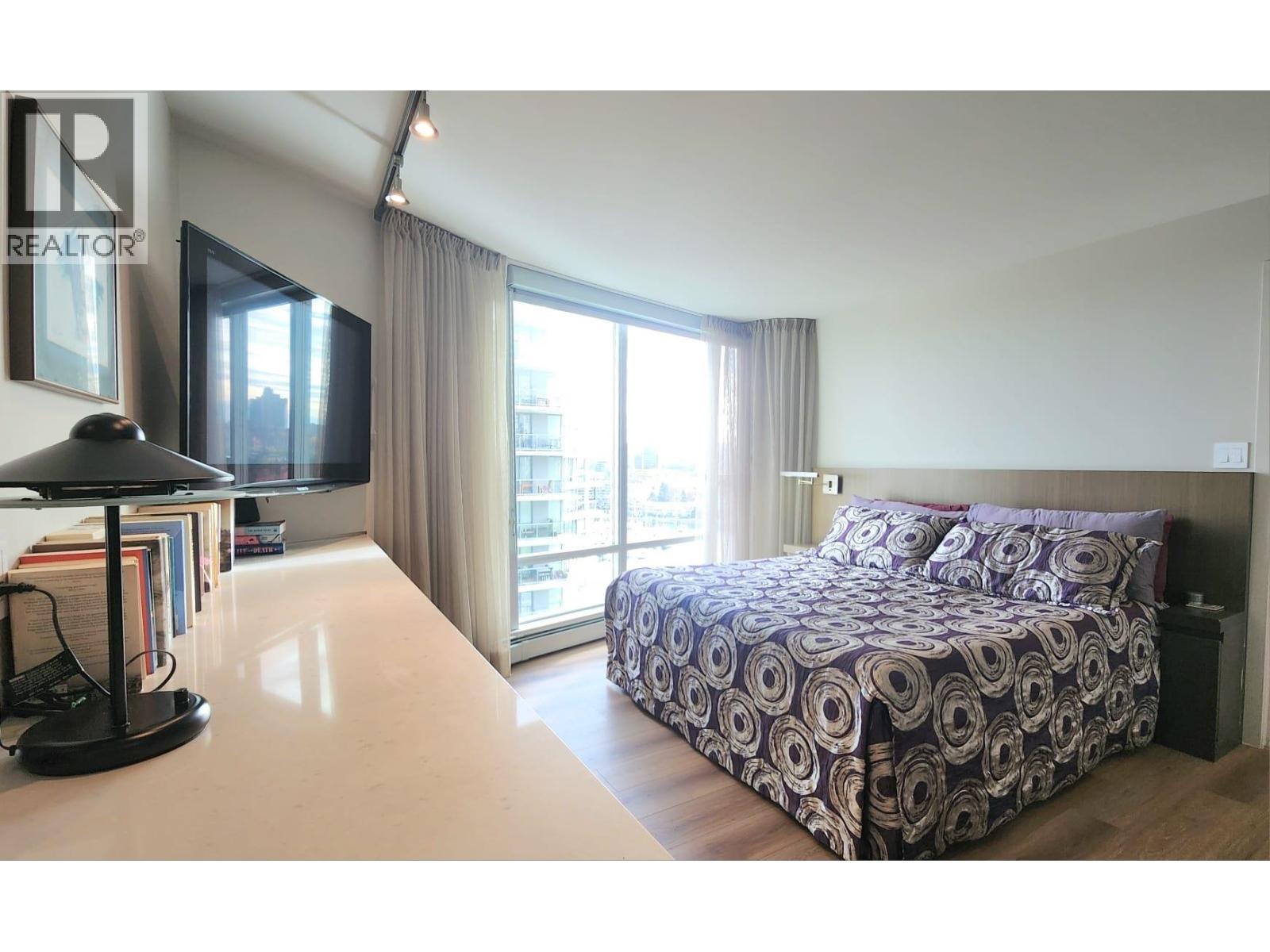 A bedroom with a large bed and a desk with a lamp.