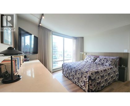 A bedroom with a large bed and a desk with a lamp.