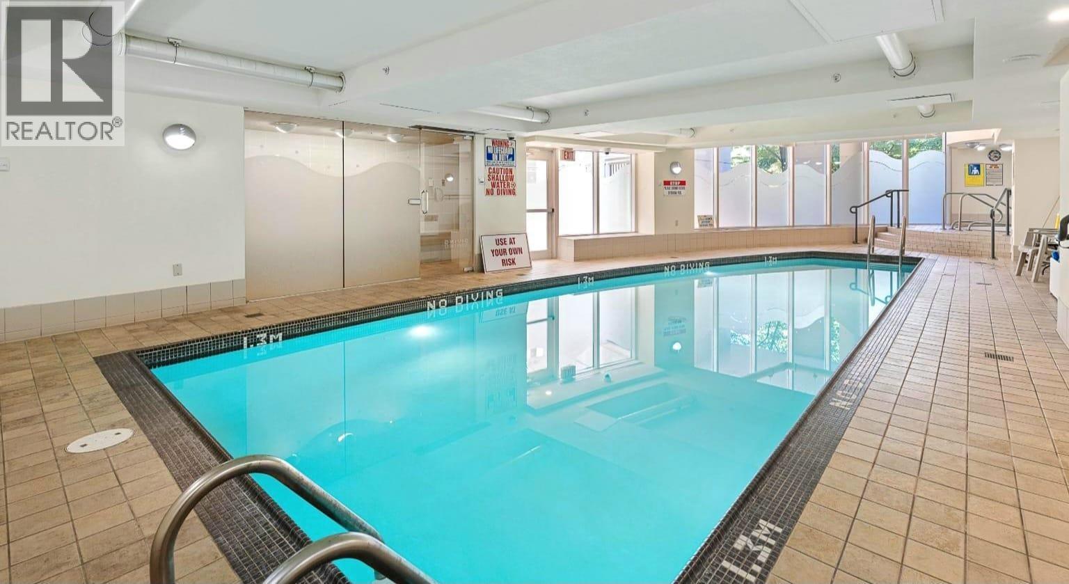 A large indoor swimming pool with a glass wall on one side.