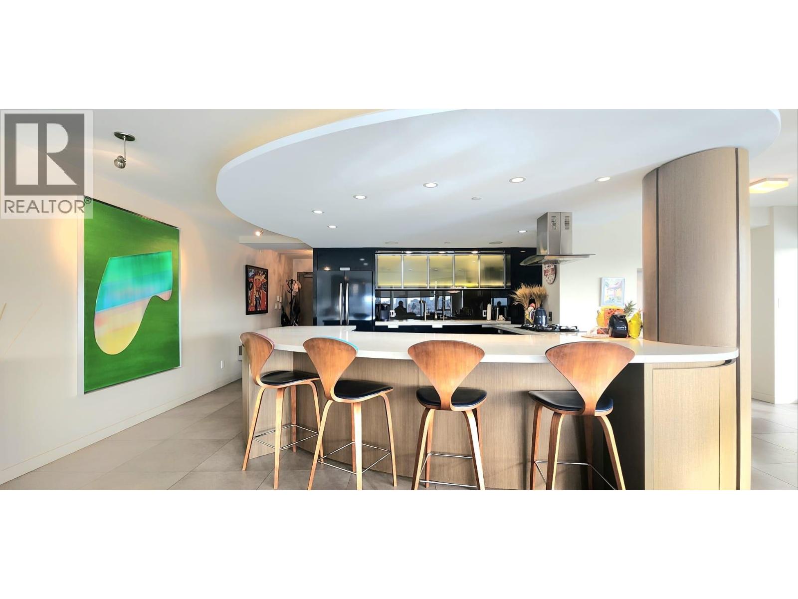 A modern kitchen with a bar area and a painting on the wall.