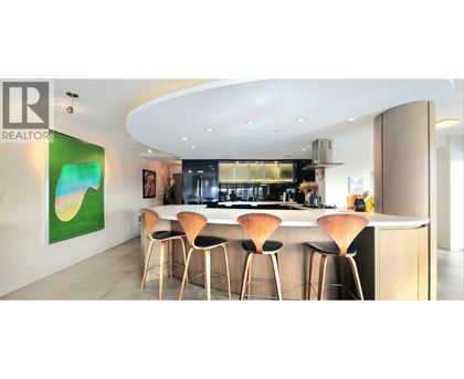 A modern kitchen with a bar area and a painting on the wall.