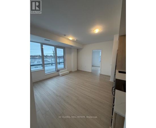 A spacious room with wooden flooring and large windows.