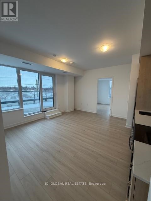 A spacious room with wooden flooring and large windows.