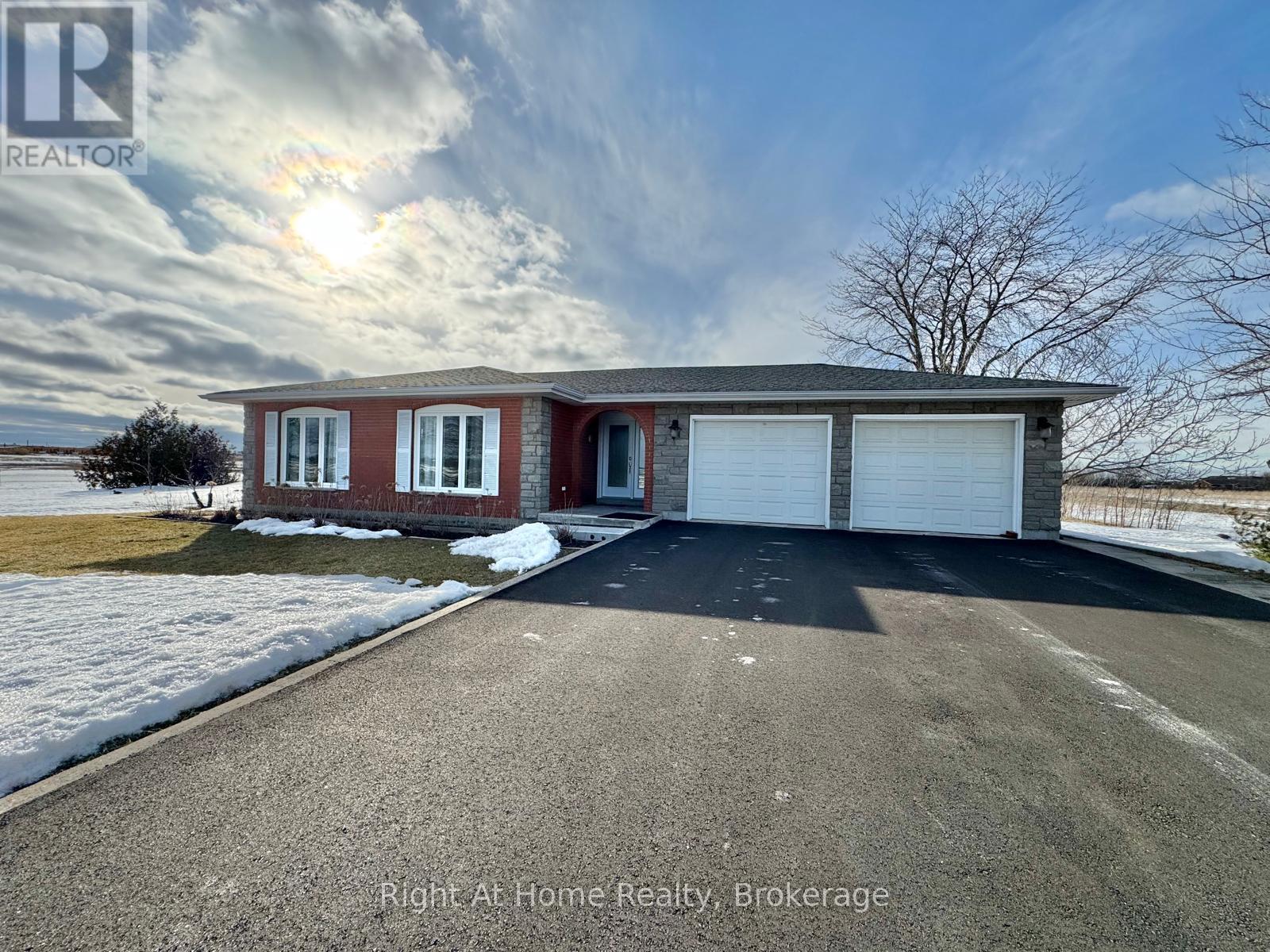A house with a red brick exterior and a white garage door is for sale with Right At Home Realty in Brokerage.