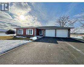 A house with a red brick exterior and a white garage door is for sale with Right At Home Realty in Brokerage.