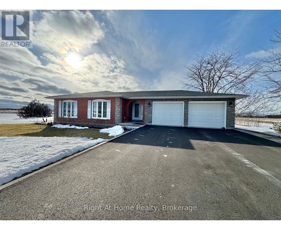 A house with a red brick exterior and a white garage door is for sale with Right At Home Realty in Brokerage.