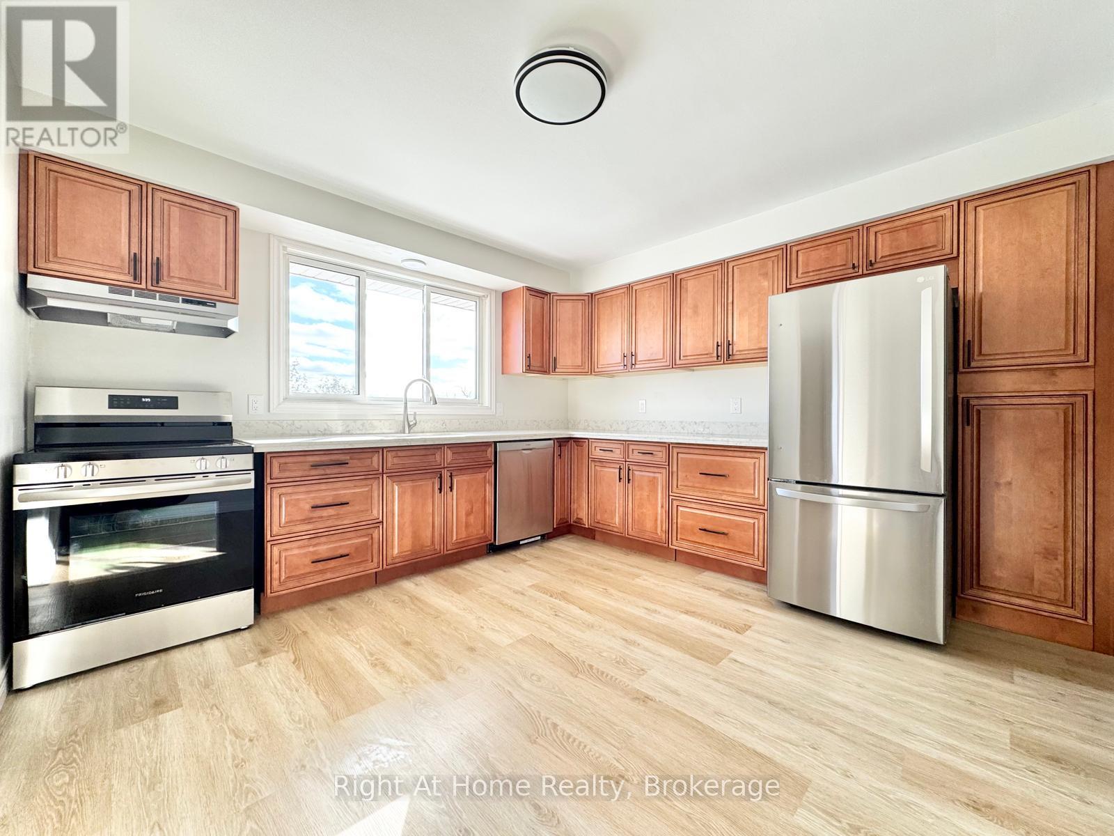 A kitchen with wooden cabinets and a stainless steel refrigerator.
