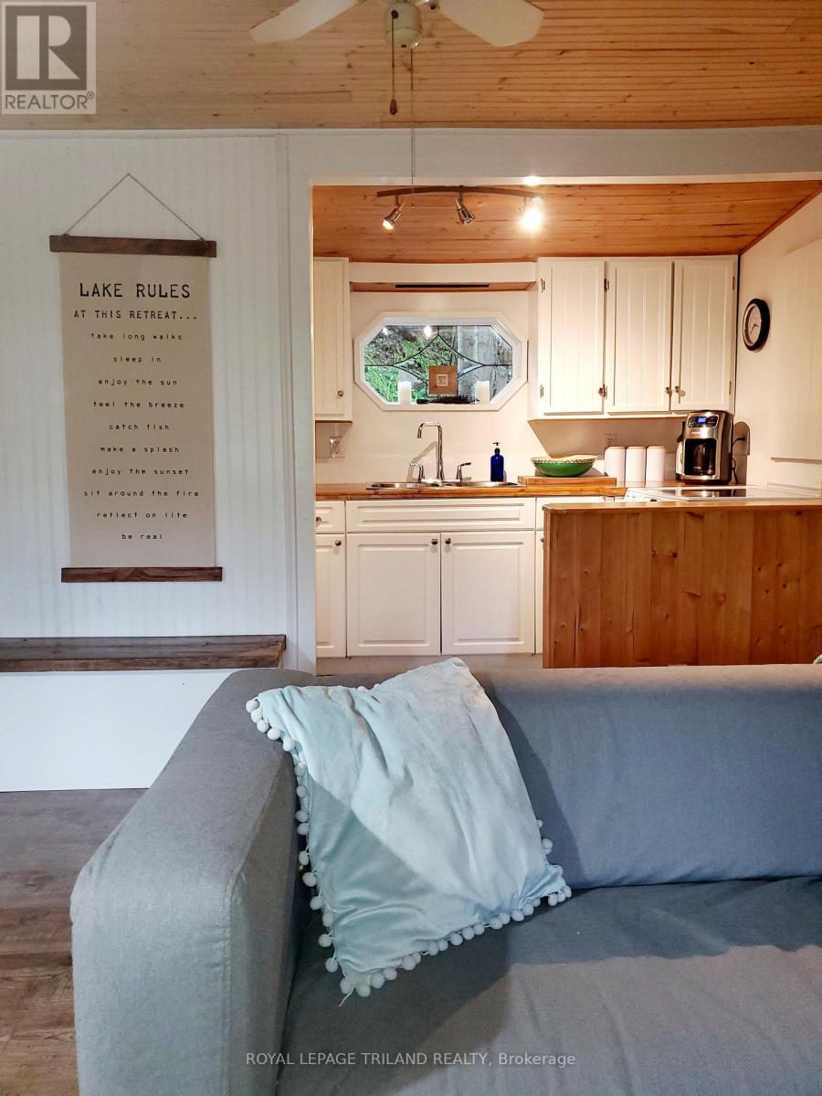 A living room with a grey couch and a sign that says Lake Rules.