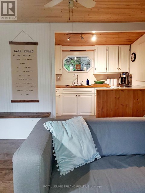 A living room with a grey couch and a sign that says Lake Rules.