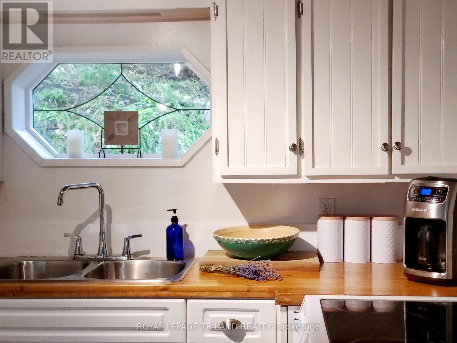 A kitchen with a sink, a bowl, and a coffee maker.