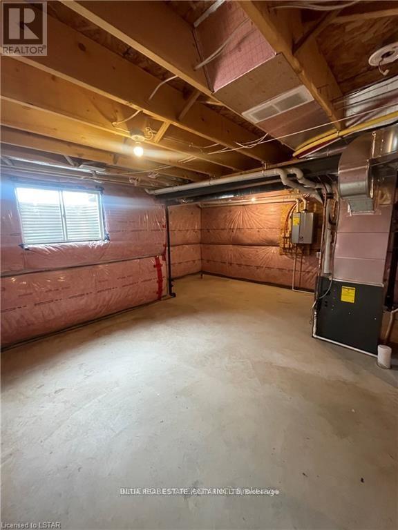 A spacious unfinished basement with a window and exposed pipes.