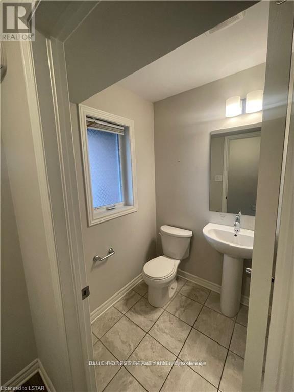 A small bathroom with a toilet, sink, and window.