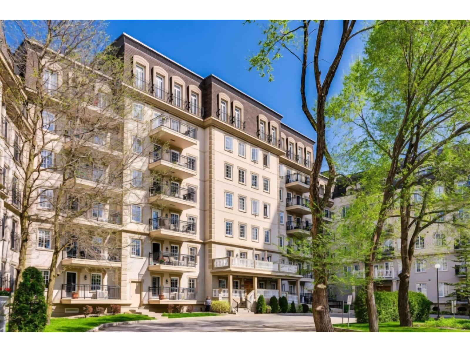 A large apartment building with balconies and trees in front.