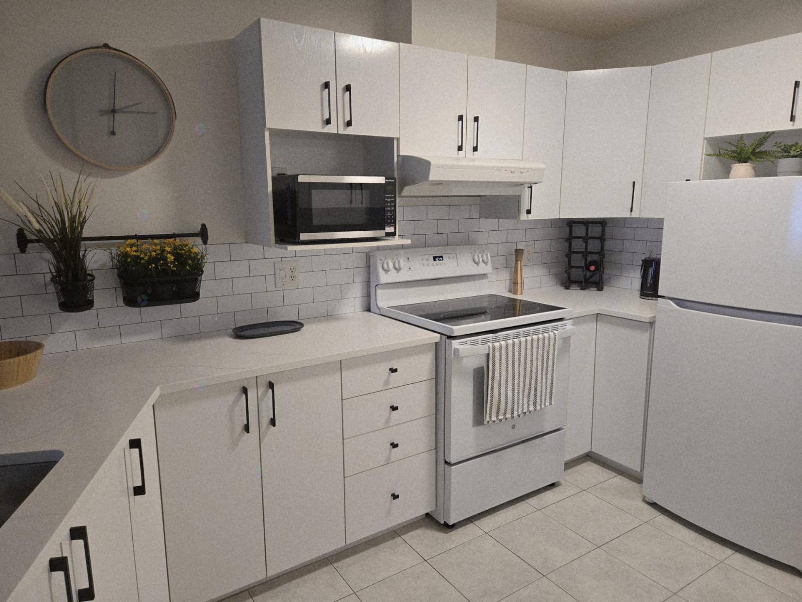 A white kitchen with a microwave, oven, and refrigerator.