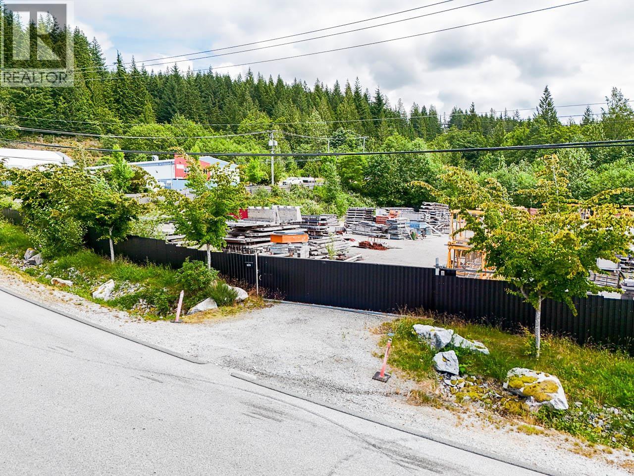 A road with a fence and a construction site in the background.