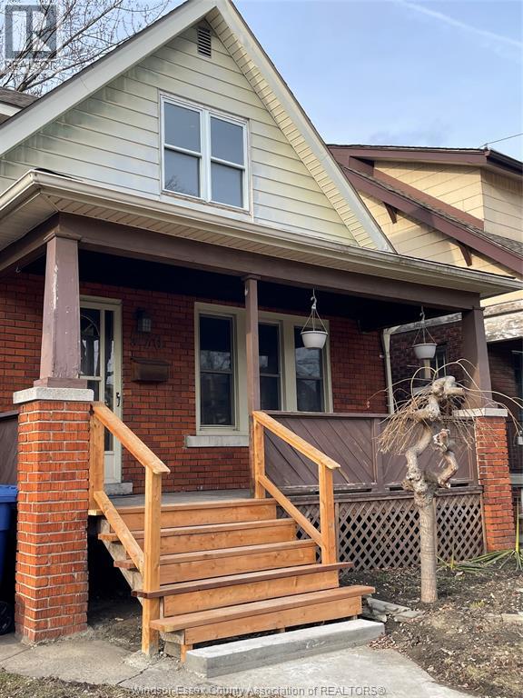 A house with a wooden porch and a blue trash can in front.