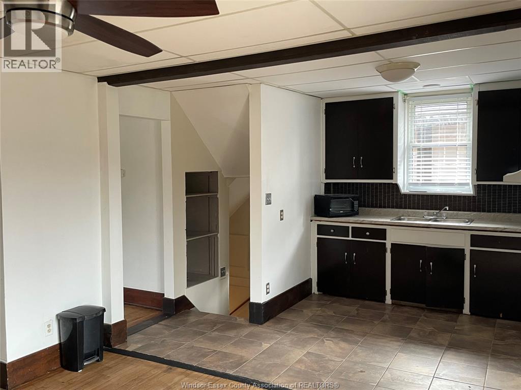 A kitchen with black cabinets and a white ceiling fan.