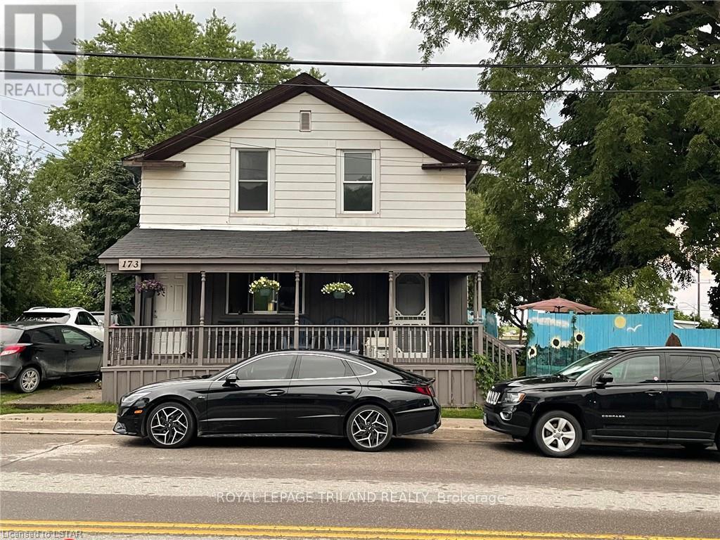 A black car is parked in front of a white house.