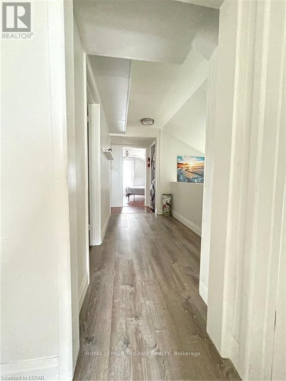 A long hallway with wood floors and white walls.