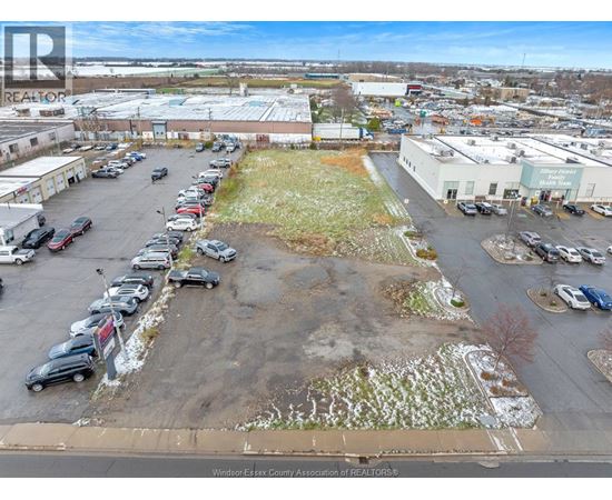 A parking lot with a grassy area in the middle and several cars parked.