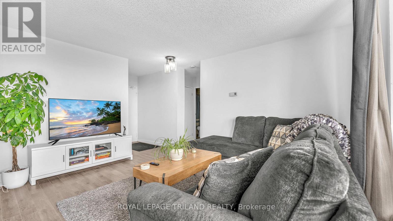 A living room with a grey couch and a flat screen TV.