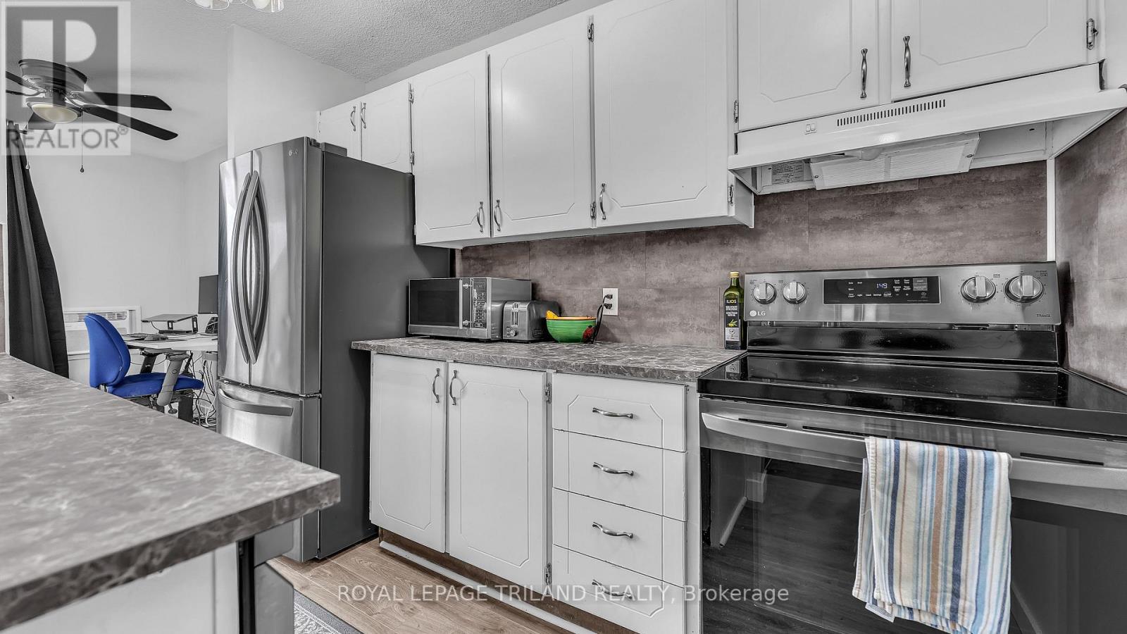 A modern kitchen with white cabinets and a marble countertop.