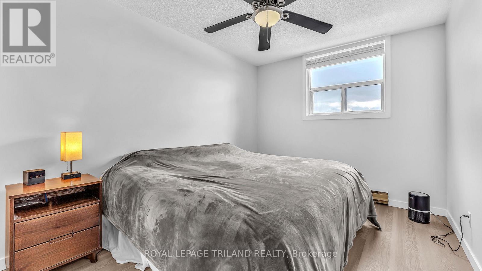 A bedroom with a bed, nightstand, and window.