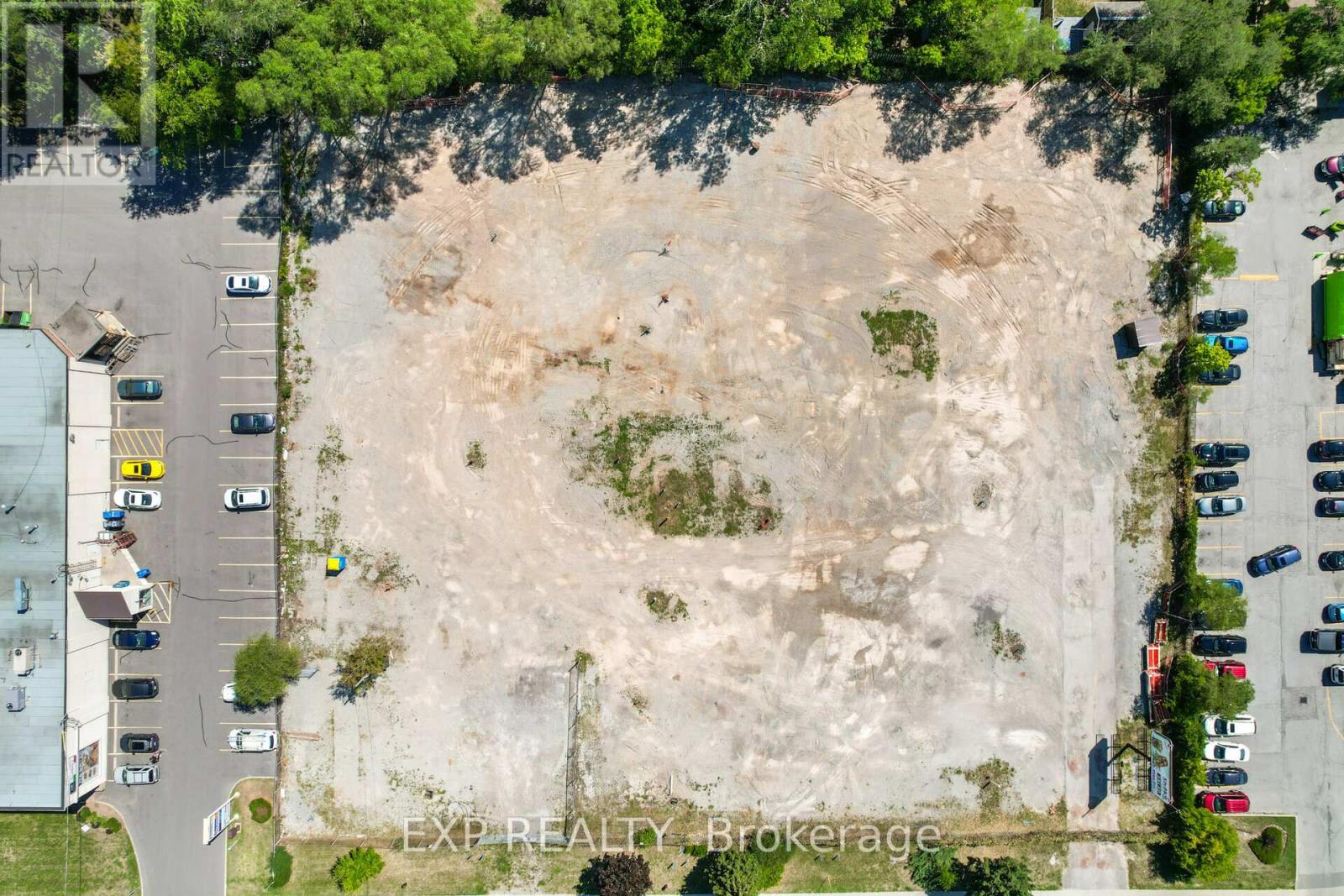 An aerial view of a parking lot with a large expanse of dirt in the center.