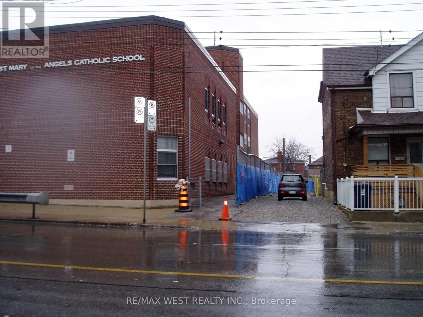 A wet street in front of a brick building with the words "Angels Catholic School" on it.
