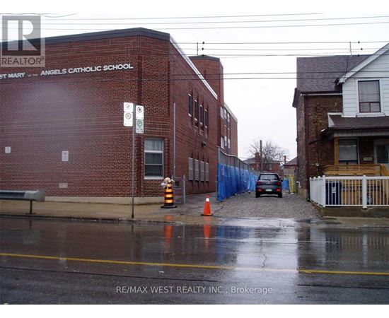 A wet street in front of a brick building with the words "Angels Catholic School" on it.