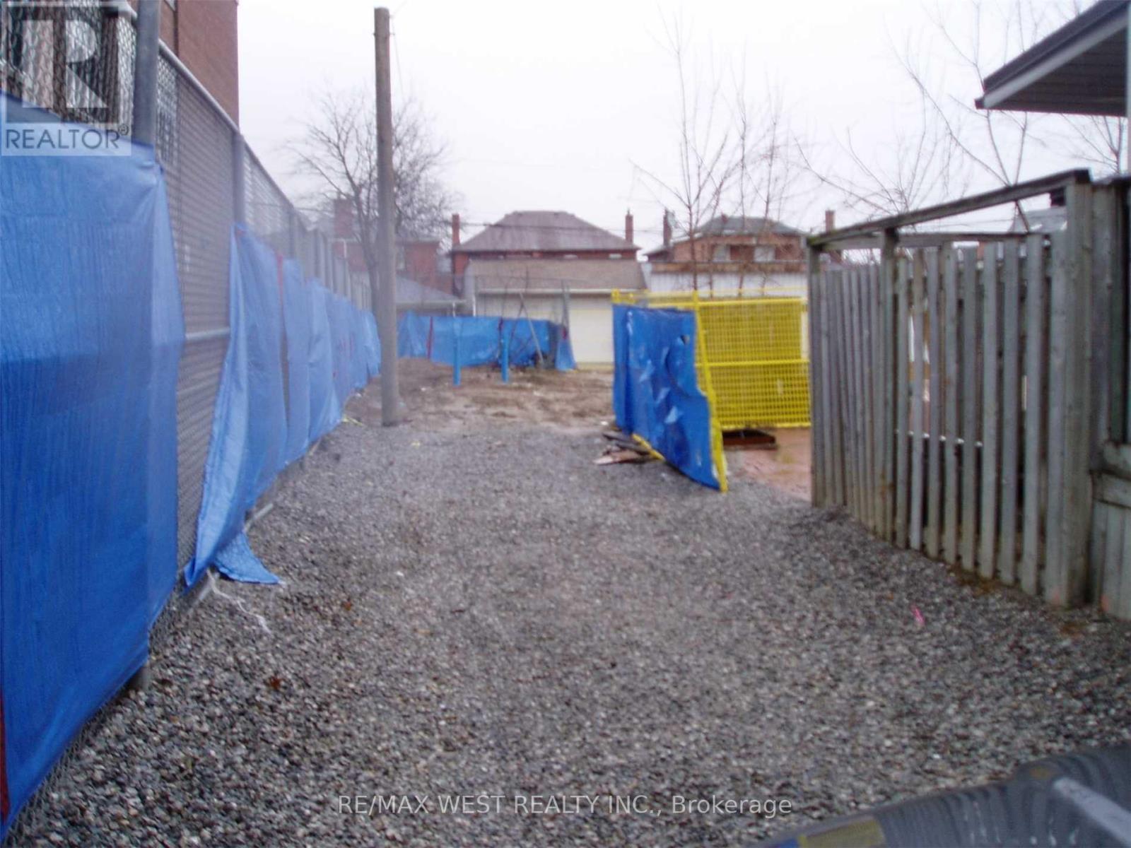 A gravel area with a blue tarp on the left and a yellow tarp on the right.