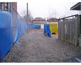 A gravel area with a blue tarp on the left and a yellow tarp on the right.