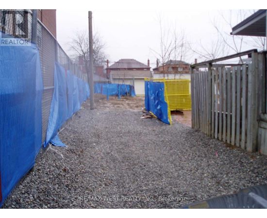 A gravel area with a blue tarp on the left and a yellow tarp on the right.